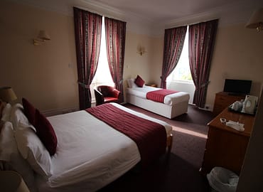 Two beds in a room overlooking a window.