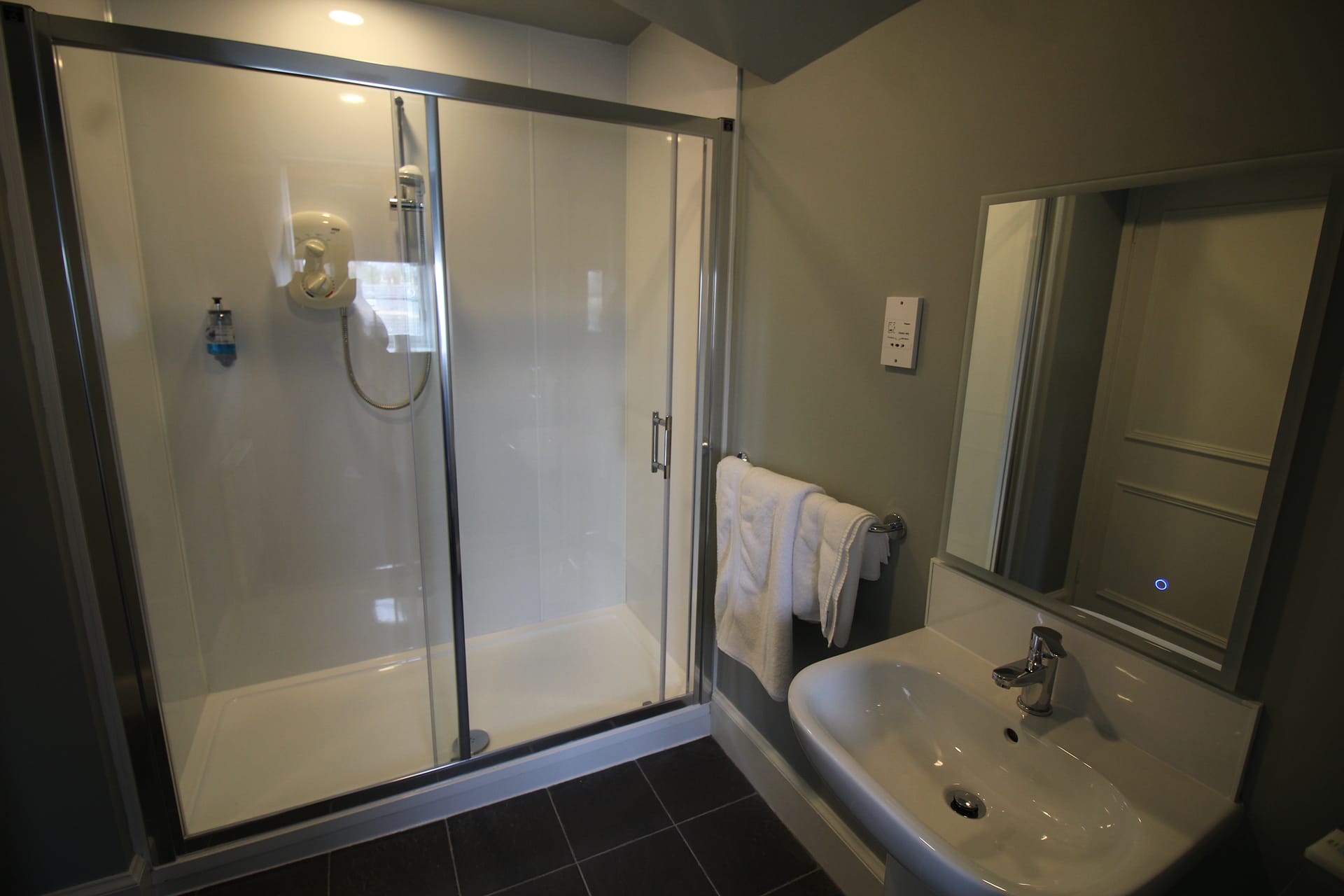 An Elgin hotel room with a shower and sink for guests to freshen up after enjoying their breakfast.
